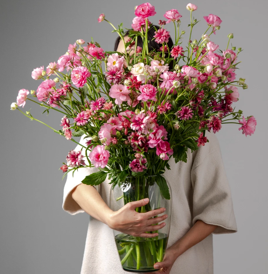 large arrangement of pink moderna dolce ranunculus in glass vase