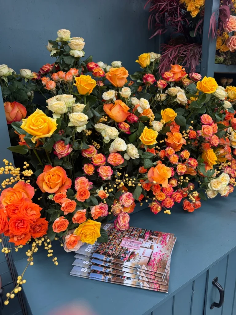 Stunning wall of orange, yellow, and cream roses displayed at International Floriculture Trade Fair with marketing materials