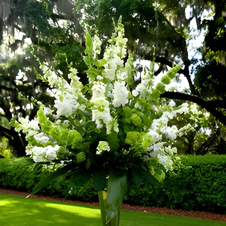 Tall St. Patrick’s Day floral arrangement featuring Bells of Ireland and white flowers in a silver vase on a pedestal outdoors
